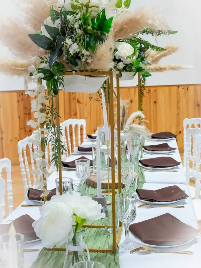 Table longue avec composition florale suspendue sur structure dorée